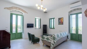 Ein Zimmer mit einer Couch, zwei Sesseln, einem Fernseher und einem Tisch.