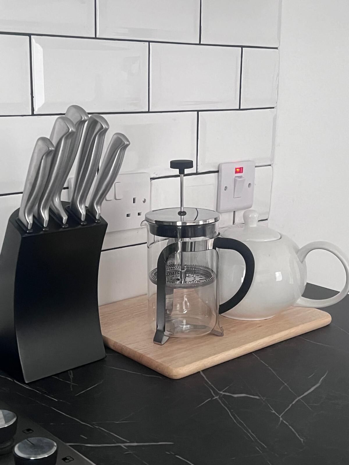 Eine Küche mit Kaffeemaschine, einem Messerblock und einem Teekessel auf einer Holzbrett.
