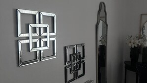 Ein Zimmer mit Heizkörper, Spiegel und drei geometrischen Wandbildern.