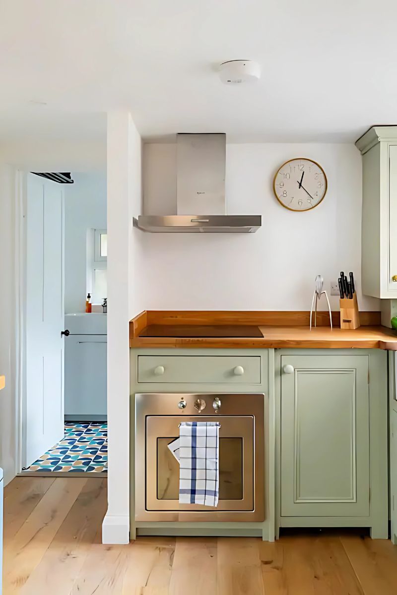 A kitchen with a wooden countertop, a clock, and a stove.