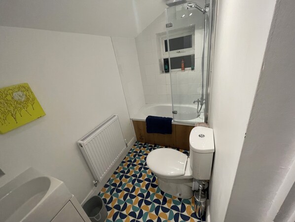 A bathroom with a bathtub, toilet, and a shower. - Stanley Road - Modern Flat in Oxford (Oxford)