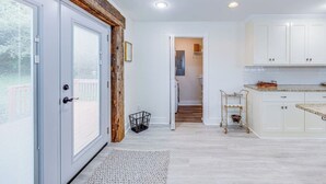 Una cocina moderna con armarios blancos, un muro decorativo de madera y una pequeña isla con carrito.