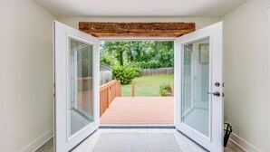 Una habitación con puerta de vidrio corrediza que da a una terraza de madera.