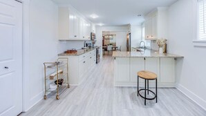 Una cocina moderna con armarios blancos, encimera de granito y una isla central con un taburete.