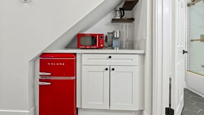 Eine kleine Küche mit einem roten Galanz-Kühlschrank, einer Mikrowelle und einer Kaffeemaschine auf einer weißen Arbeitsplatte.
