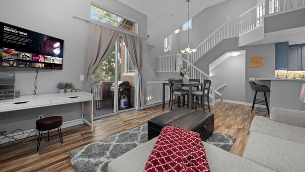 Un salon moderne doté d’un téléviseur à écran plat, d’un coin repas et d’un escalier.
