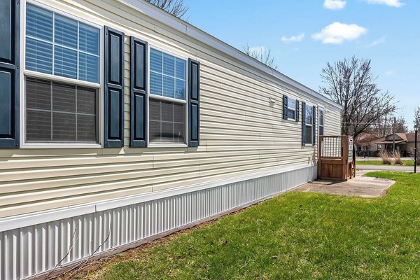 Side view highlighting the home’s length, multiple windows, and private entry steps.