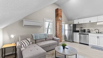 A modern loft apartment with a living area, kitchenette, and a dining space.