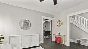 A spacious living area with a white console, a round mirror, a clock, and a staircase. - Family Friendly Home for 8 (Fort Wayne)