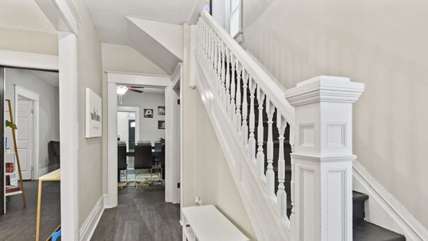 A spacious hallway with a staircase leading to a second floor. The hallway has a wooden floor and white walls, with a dining area visible in the background. - Family Friendly Home for 8 (Fort Wayne)