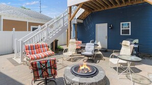 Eine Terrasse mit Gartenmöbeln, einem Feuerkorb und einer Treppe, die zu einer oberen Ebene führt.