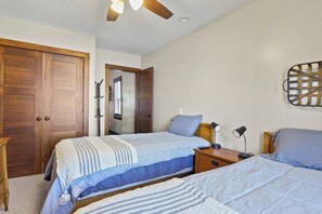Ein Schlafzimmer mit zwei Betten, einem Holzschrank, einem Deckenventilator, Nachttischlampen und einer Wandleuchte.