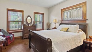 A bedroom with a bed, dresser, mirror, windows, and a ceiling fan. - Apartment Near Parkview Field | Free Parking, Downtown Area (Fort Wayne)