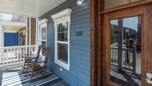 A porch with rocking chairs, a wooden door with a number, and a balcony with railings. - Apartment Near Parkview Field | Free Parking, Downtown Area (Fort Wayne)