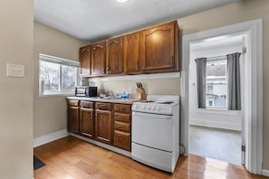 A kitchen with wooden cabinets, a white stove, and a window.