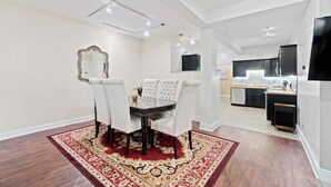 A dining area with a table and chairs, a mirror, and a kitchen in the background.