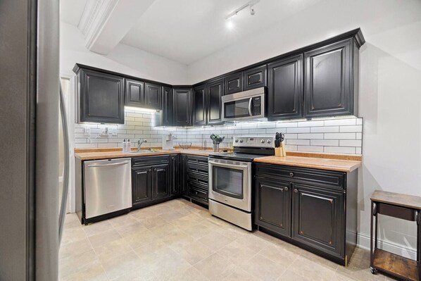 A modern kitchen with dark cabinetry, stainless steel appliances, and a tiled backsplash.