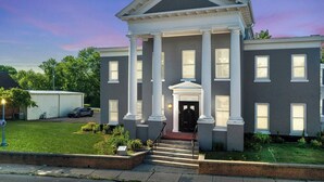 A two-story building with a central entrance flanked by columns, a flat roof, and a brick facade.