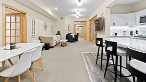 A modern interior with a dining area, sofas, a kitchen, and a TV.