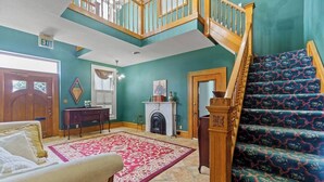 A spacious living room with a staircase, a fireplace, and a large window.