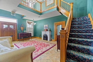 A spacious living room with a staircase, a fireplace, and a large window.