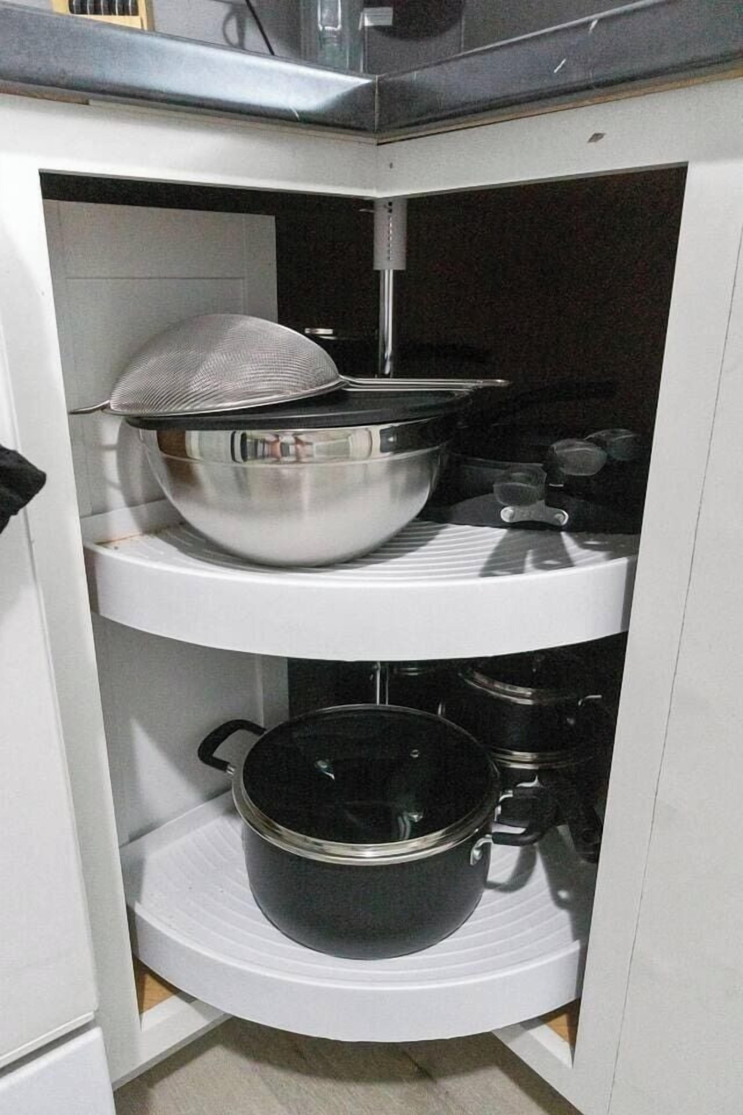 A kitchen with white cabinets, a stove, and pots on shelves.