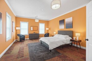 Een slaapkamer met een bed, een dressoir, een stoel en twee bedlampjes.