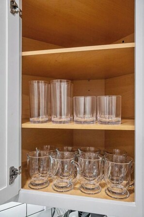 Un meuble avec des étagères où sont rangés des verres transparents.