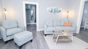 En moderne stue med en grå sofa, en matchende lænestol og et træbord.