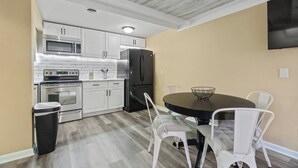 A compact kitchen with white cabinets, a microwave, a refrigerator, and a dining table with chairs. - Downtown Apartment 3 in Historic Mansion | Free Parking (Fort Wayne)