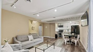 A modern living room with a sofa, coffee table, and dining area with chairs. - Downtown Apartment 3 in Historic Mansion | Free Parking (Fort Wayne)