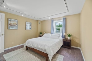 A bedroom with a bed, bedside tables, a window with curtains, and artwork on the walls. - Downtown Apartment 3 in Historic Mansion | Free Parking (Fort Wayne)