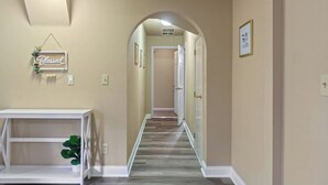 A hallway with a white console table, a potted plant, a 'Blessed Beyond Measure' sign, and a door at the end. - Downtown Apartment 3 in Historic Mansion | Free Parking (Fort Wayne)