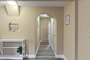 A hallway with a white console table, a potted plant, a 'Blessed Beyond Measure' sign, and a door at the end.