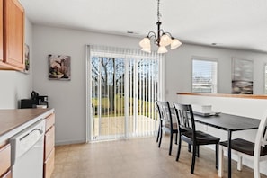 A modern kitchen with a dining area, a sliding glass door to a patio, and a pendant light fixture. - Comfortable Home for 5 | Garage, Private Yard (Fort Wayne)