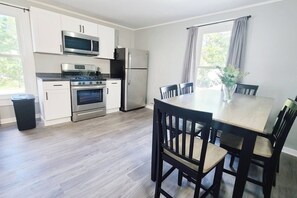 A modern kitchen with white cabinets, stainless steel appliances, and a dining area with a wooden table and chairs.