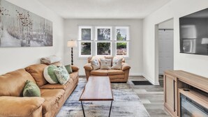 A spacious living room with a large window, two sofas, a coffee table, and a fireplace.