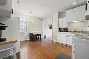 Une cuisine moderne avec des meubles blancs, un coin repas comprenant une table et des chaises, et un plancher en bois.