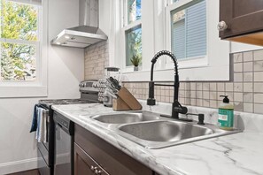 A kitchen with two sinks, a stove, and a window with a view of trees.