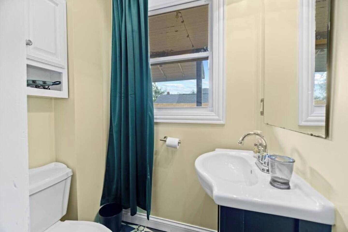 Une salle de bain avec des toilettes, un lavabo et une fenêtre.