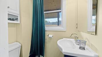 Une salle de bain avec des toilettes, un lavabo et une fenêtre.