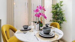Una mesa de comedor dispuesta con platos, cuencos, cubiertos y una botella de champán.