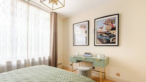 Un dormitorio con una cama, un escritorio y dos cuadros en la pared.