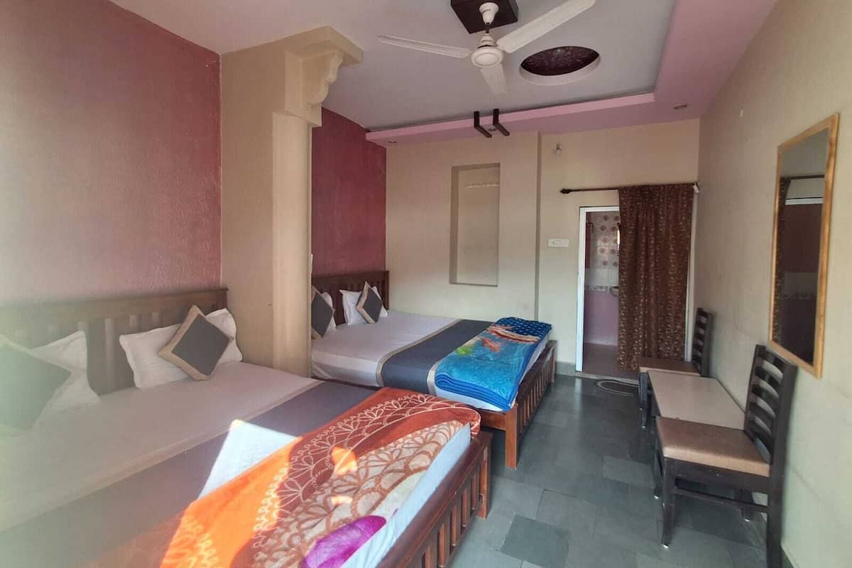 Habitación de hotel con dos camas, una silla, ventilador de techo y baño visible a través de una puerta abierta.