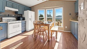 A kitchen with wooden cabinets, a stove, and a dining area with a table and chairs. - Mountain Farm Stay, Alpacas & Views, Royal Gorge 15min (Cañon City)