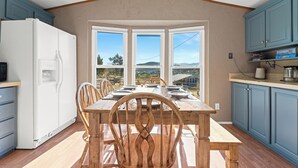 A kitchen with a dining table, chairs, a refrigerator, and a bay window with a view. - Mountain Farm Stay, Alpacas & Views, Royal Gorge 15min (Cañon City)