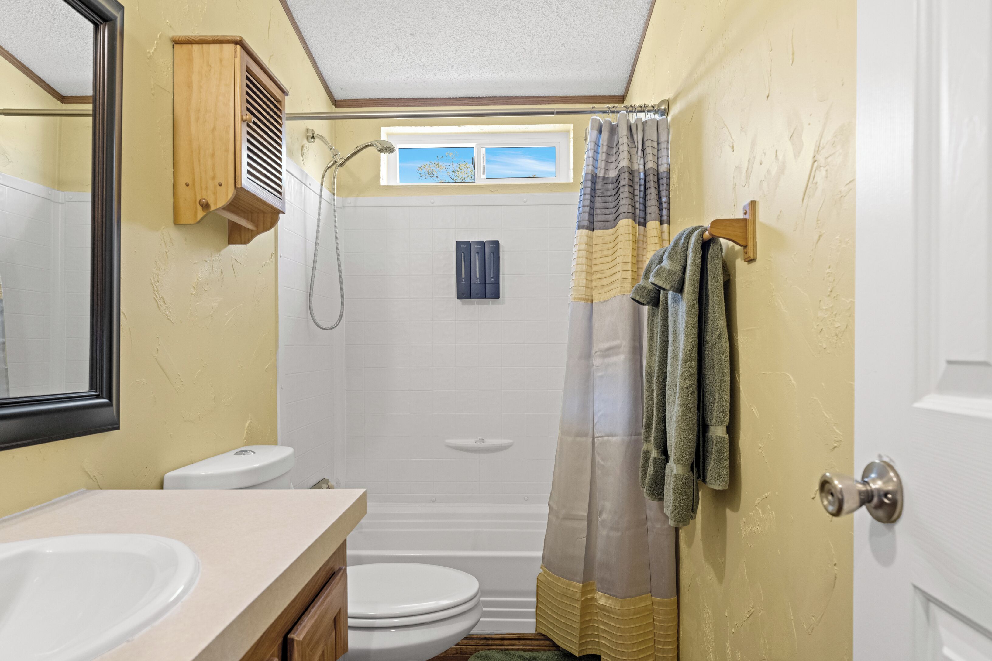 A bathroom with a shower, toilet, and sink.