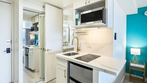 Une cuisine compacte avec des meubles blancs, un four à micro-ondes encastré et un évier.