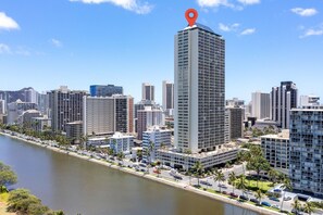 A high-rise building with a prominent red marker, surrounded by other buildings and a waterfront.