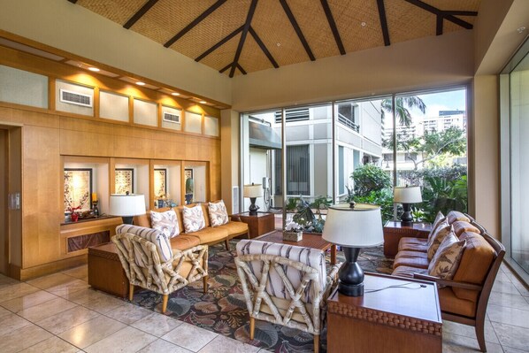A lobby with a seating area, a reception desk, and large windows offering a view of the outside.